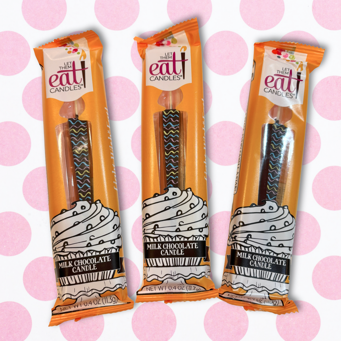Three individually wrapped dark chocolate party candles with colorful waves arranged in fan shape on a white background with pink polka-dots. Packaging is orange with a window to showcase product.