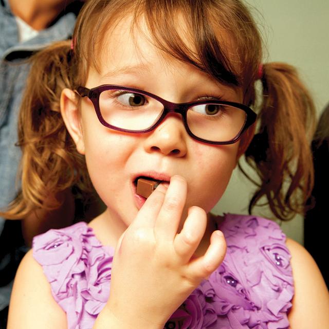 Young girl with pigtails and glasses eating Edible Milk Chocolate Candle | Let Them Eat Candles