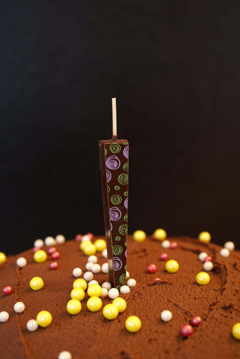 Edible Dark Chocolate Candle with purple/green spirals on chocolate frosted cake | Let Them Eat Candles