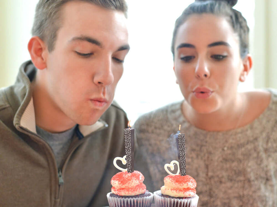 Couple blowing out Edible Dark Chocolate Candles with white sprinkles on cupcakes | Let Them Eat Candles